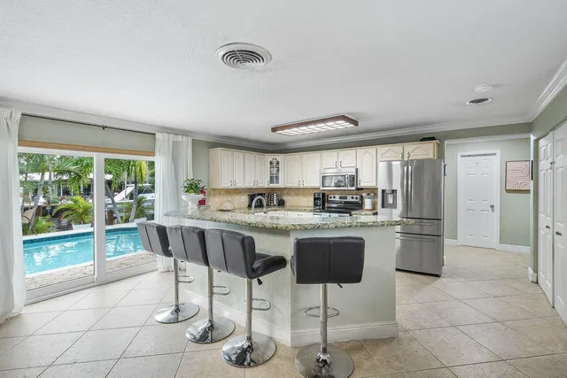a kitchen with a sink a refrigerator and chairs