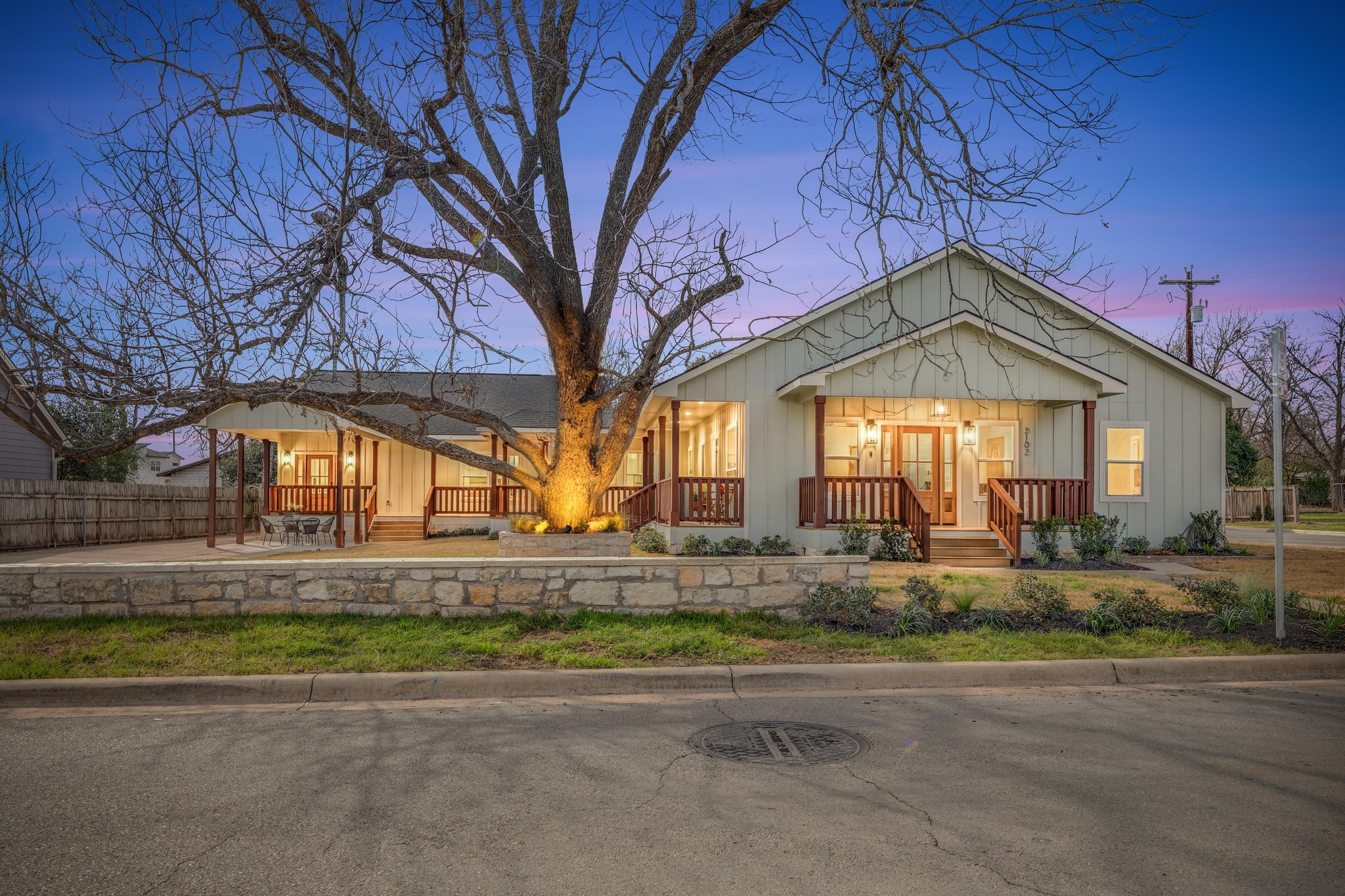 Twilight view of front facade featuring a porch and board and batten siding