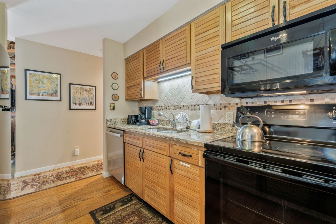 2025 Walton Creek Road, Unit 401 Steamboat Springs, CO 80487 - Photo 13 of 38 a kitchen with granite countertop stainless steel appliances and wooden cabinets
