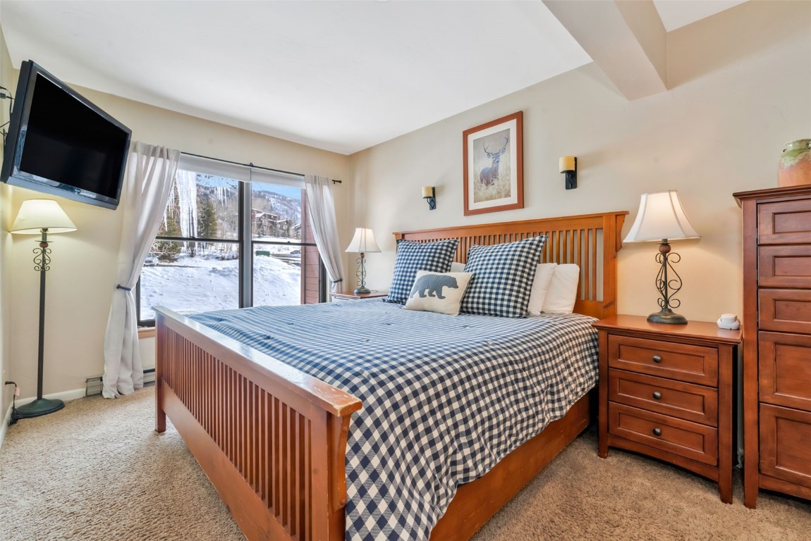 2025 Walton Creek Road, Unit 401 Steamboat Springs, CO 80487 - Photo 15 of 38 a bedroom with a bed and a flat tv screen on dresser