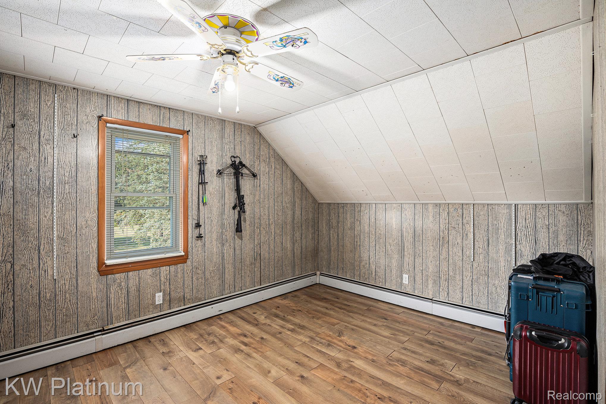 8060 Brockway Road Melvin, MI 48454 - Photo 17 of 39 Additional living space featuring wood-type flooring, baseboard heating, vaulted ceiling, wood walls, and ceiling fan