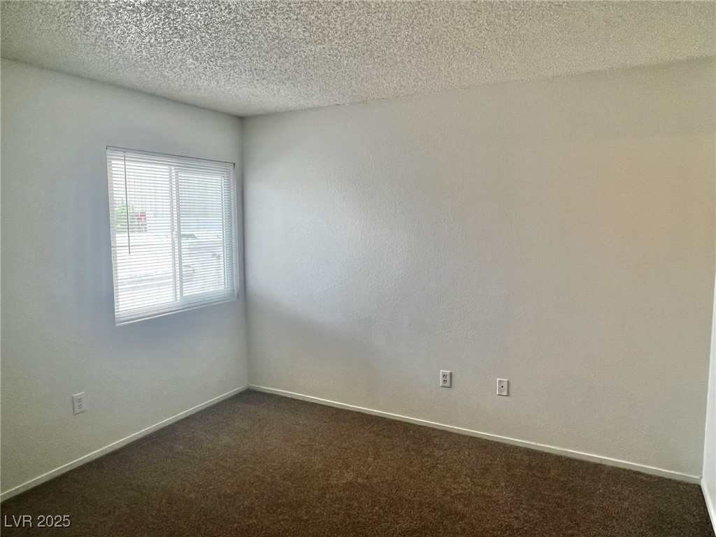 5304 Harmony Street, Unit HOME Las Vegas, NV 89107 - Photo 12 of 17 Unfurnished room featuring dark colored carpet and a textured ceiling