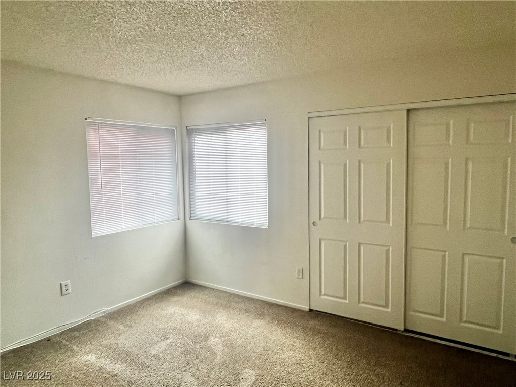 5304 Harmony Street, Unit HOME Las Vegas, NV 89107 - Photo 14 of 17 Unfurnished bedroom with carpet flooring, a textured ceiling, and a closet