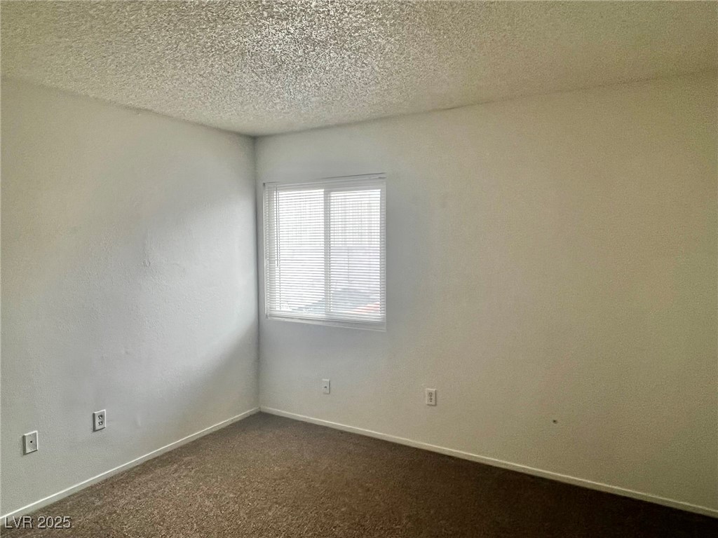 5304 Harmony Street, Unit HOME Las Vegas, NV 89107 - Photo 16 of 17 Empty room with dark colored carpet and a textured ceiling