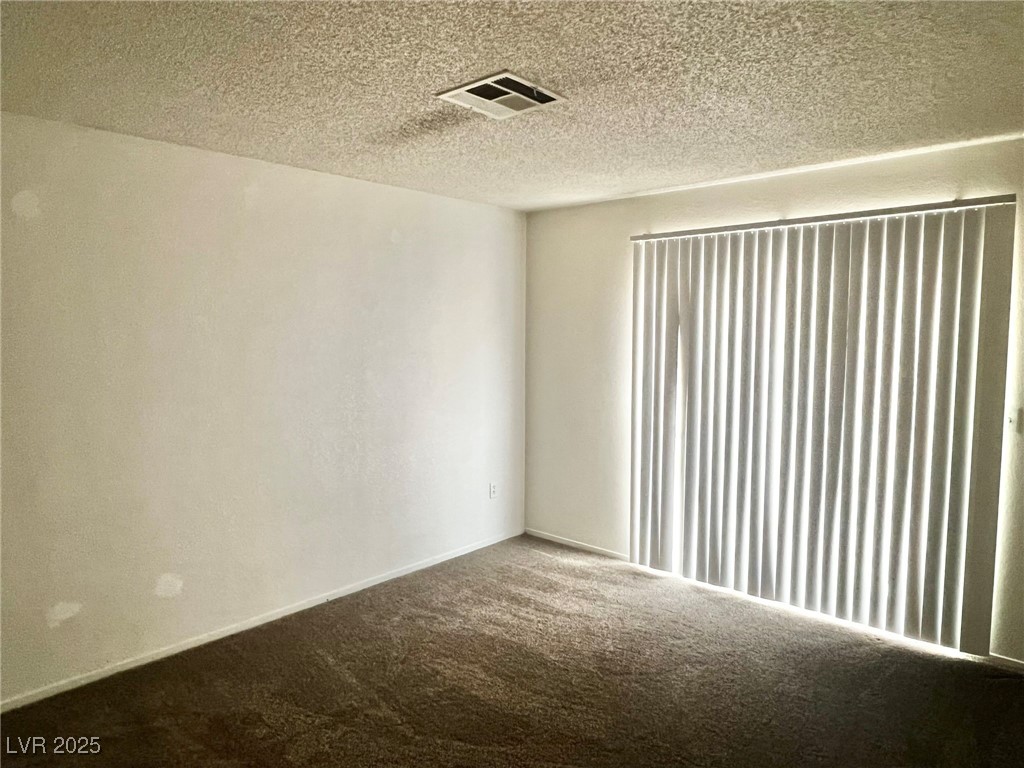 5304 Harmony Street, Unit HOME Las Vegas, NV 89107 - Photo 8 of 17 Carpeted empty room featuring a textured ceiling