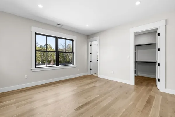 a view of an empty room with a window and wooden floor
