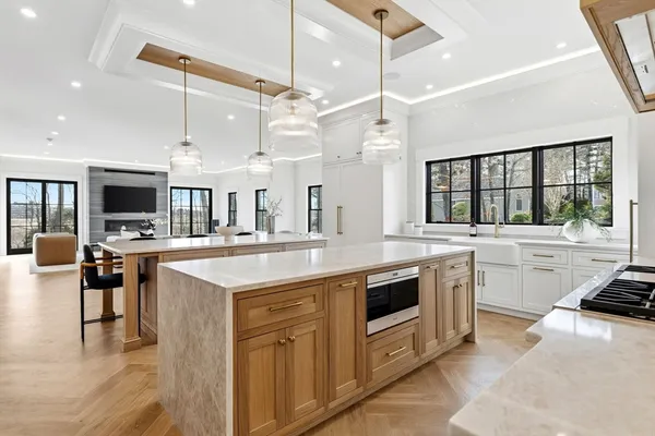 a kitchen with stainless steel appliances kitchen island granite countertop a stove top oven a sink dishwasher and white cabinets with wooden floor