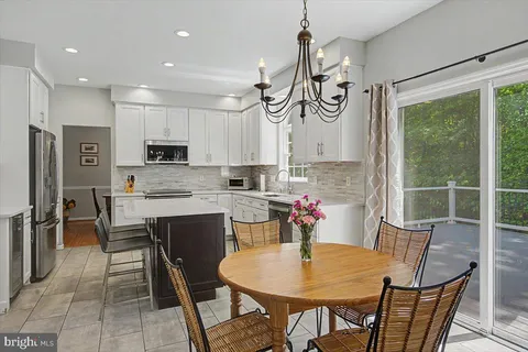 a kitchen with stainless steel appliances granite countertop a table chairs microwave and sink