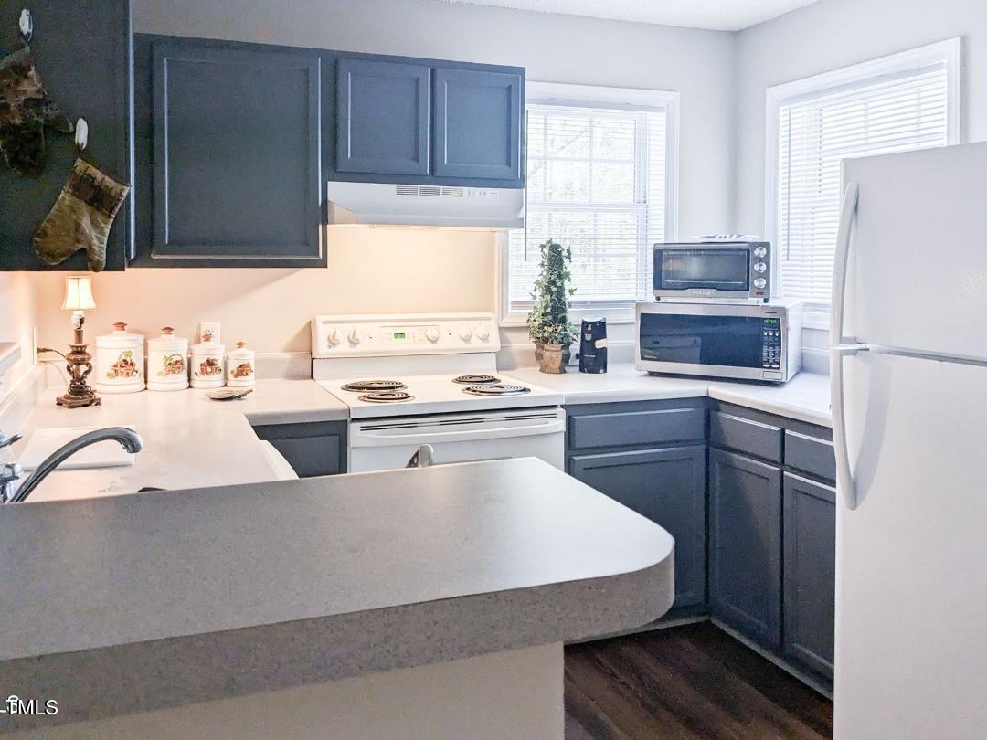 1911 Wolf Tech Lane, Unit 204C Raleigh, NC 27603 - Photo 5 of 18 a kitchen with a sink a stove a refrigerator and cabinets