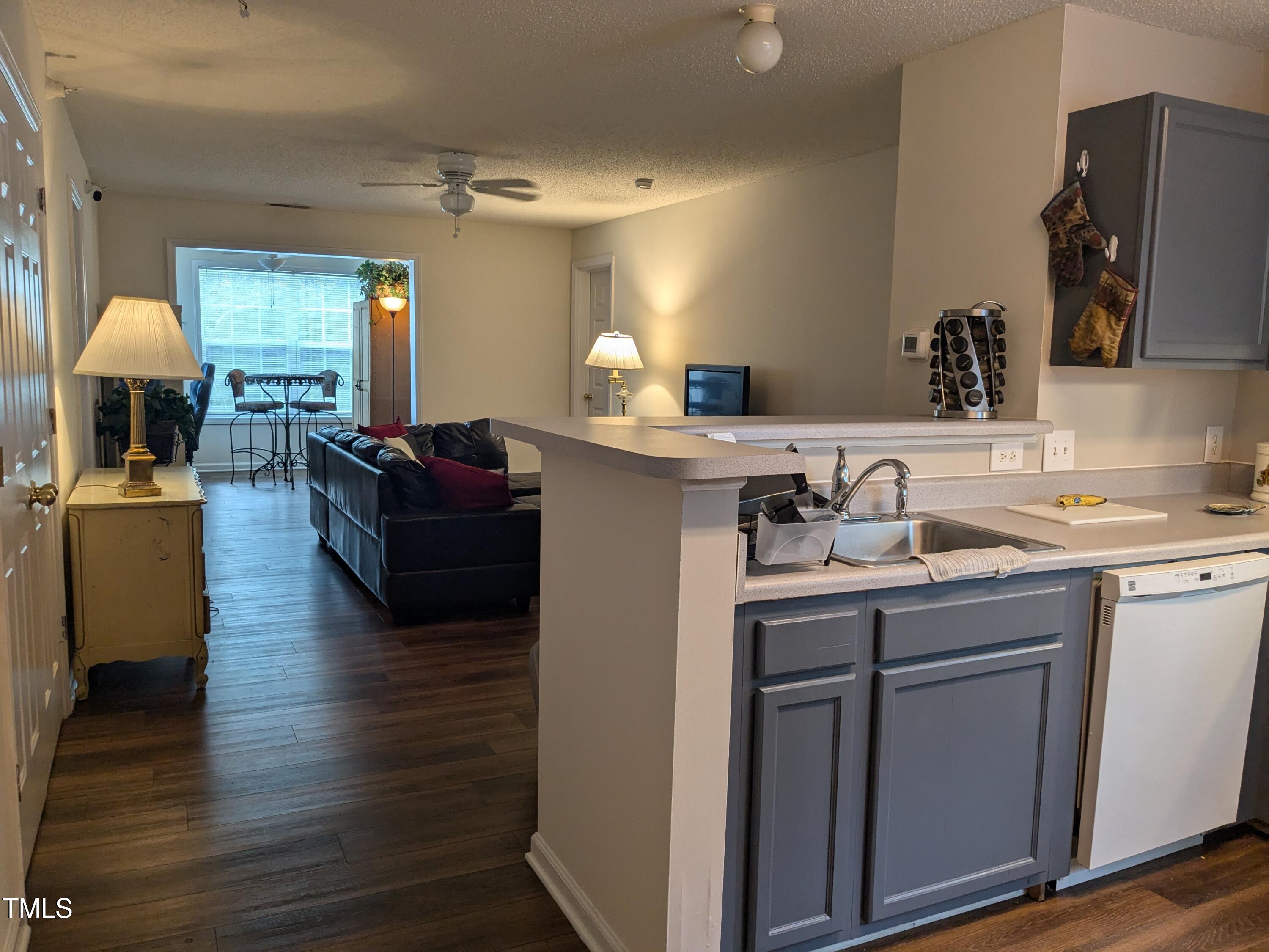 1911 Wolf Tech Lane, Unit 204C Raleigh, NC 27603 - Photo 7 of 18 a kitchen with kitchen island granite countertop a sink cabinets and wooden floor