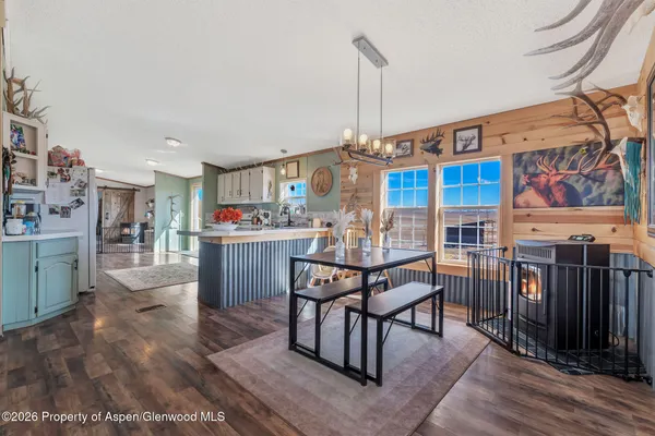 a open kitchen with stainless steel appliances granite countertop a stove top oven a dining table and chairs with wooden floor