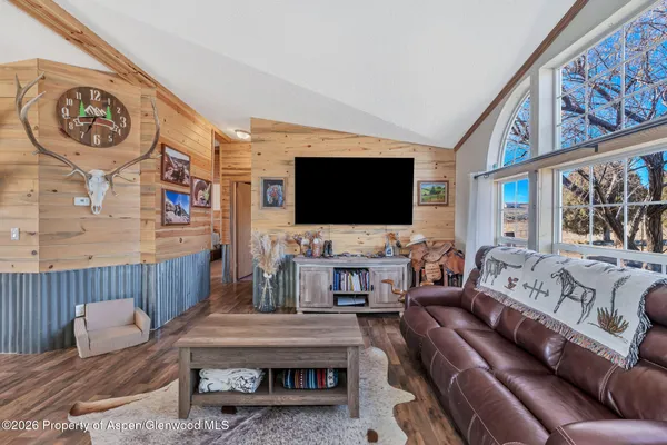 a living room with furniture a flat screen tv and a floor to ceiling window