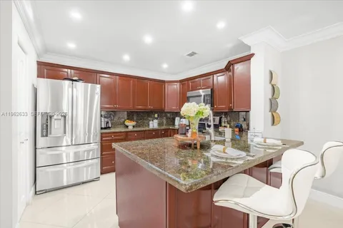 a kitchen with stainless steel appliances granite countertop a refrigerator a sink a stove a dining table and chairs