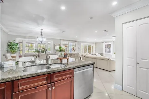 a dining hall with stainless steel appliances granite countertop a sink and a white cabinets