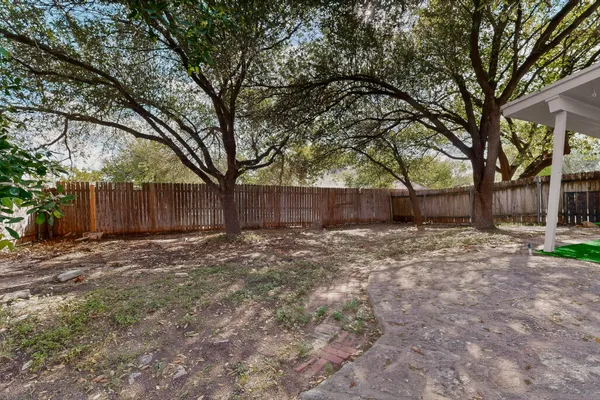 a view of backyard with large trees and wooden fence