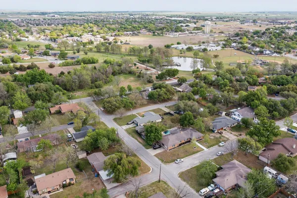 a view of a backyard with large trees and wooden fence
