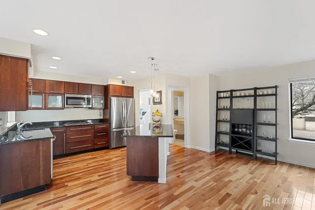a large kitchen with stainless steel appliances granite countertop a stove and a wooden floors