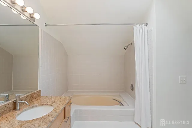a bathroom with a granite countertop sink and a bathtub
