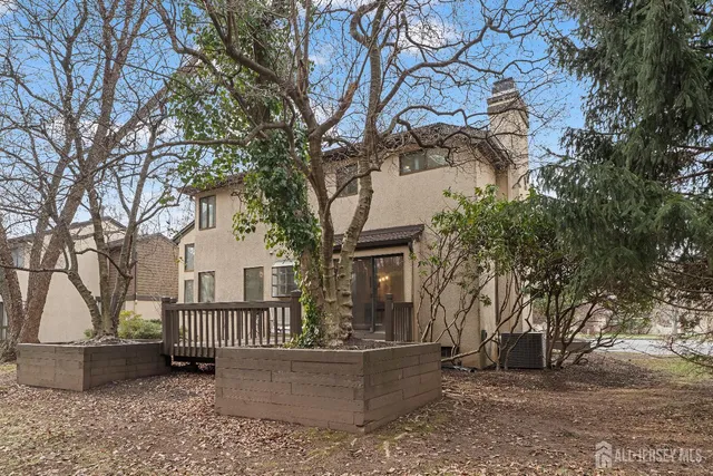 a view of a house with large windows and a tree