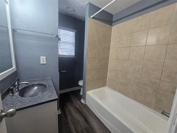 a bathroom with a granite countertop sink toilet and bathtub