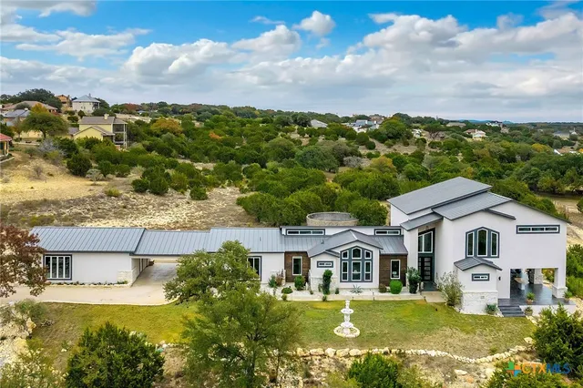 a view of a white house with a big yard and potted plants