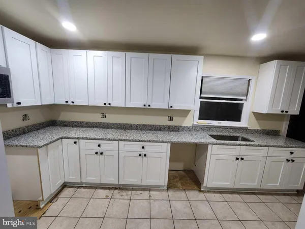 a kitchen with granite countertop a sink a stove top oven and cabinets