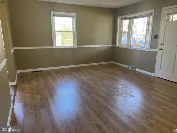 a view of an empty room with wooden floor and stairs
