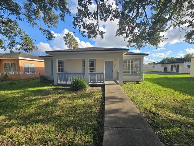 a view of a house with a small yard plants and a large tree