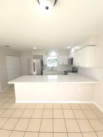 a large white kitchen with kitchen island cabinets and a sink