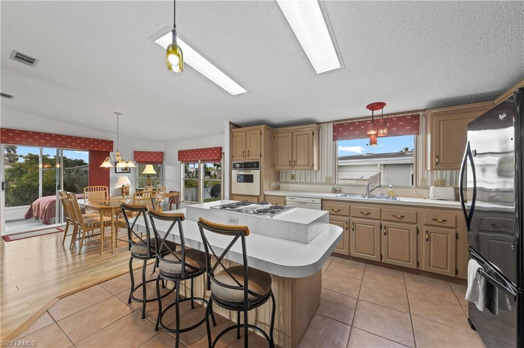 265 Riverwood Road Naples, FL 34114 - Photo 5 of 31 a dining hall with stainless steel appliances granite countertop a sink a stove a dining table and chairs with wooden floor
