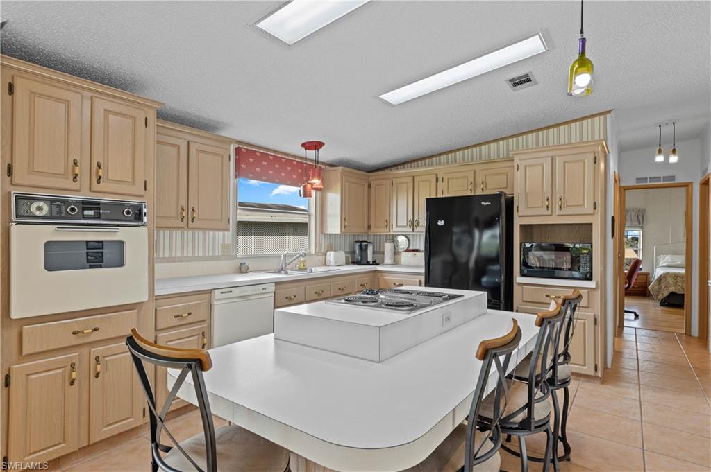 265 Riverwood Road Naples, FL 34114 - Photo 7 of 31 a kitchen with a refrigerator a stove a sink dishwasher and white cabinets with wooden floor