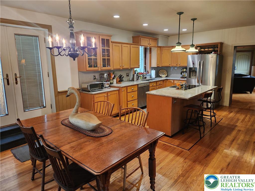 861 Municipal Road Walnutport, PA 18088 - Photo 27 of 94 a kitchen with stainless steel appliances granite countertop a stove refrigerator a dining table and chairs with wooden floor