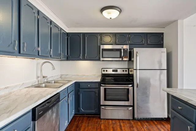 a kitchen with kitchen island granite countertop stainless steel appliances and wooden cabinets
