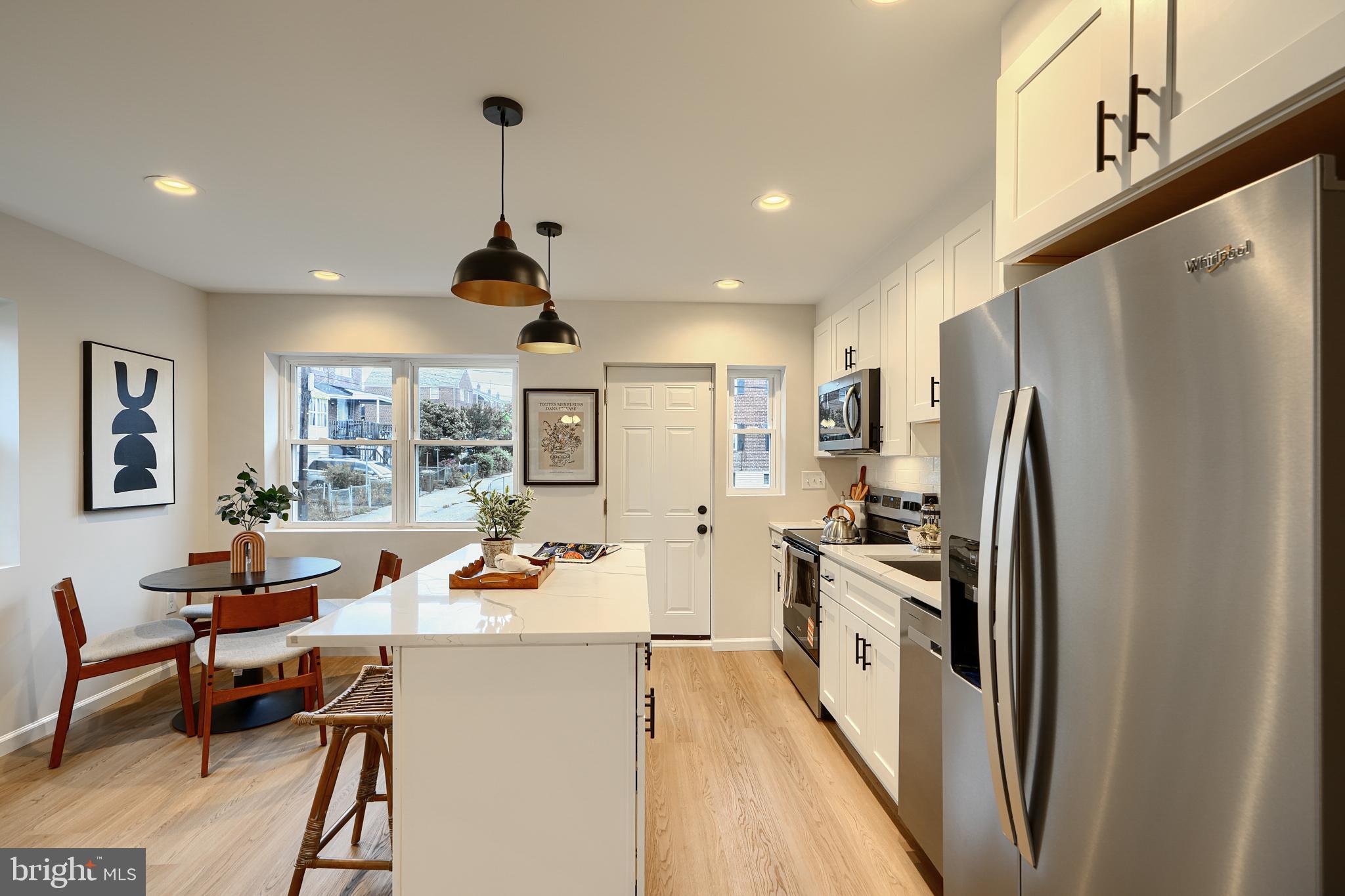 3934 Rokeby Road Baltimore, MD 21229 - Photo 14 of 38 a kitchen with a refrigerator a stove and white cabinets with wooden floor