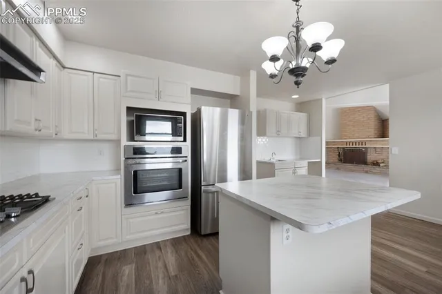 a kitchen with granite countertop stainless steel appliances a table and refrigerator