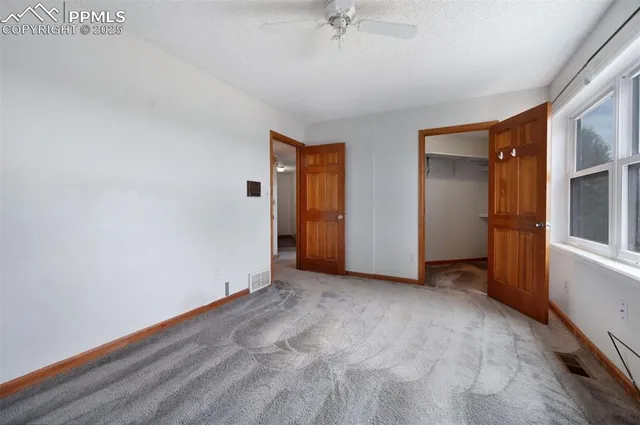 an empty room with closet and a chandelier fan