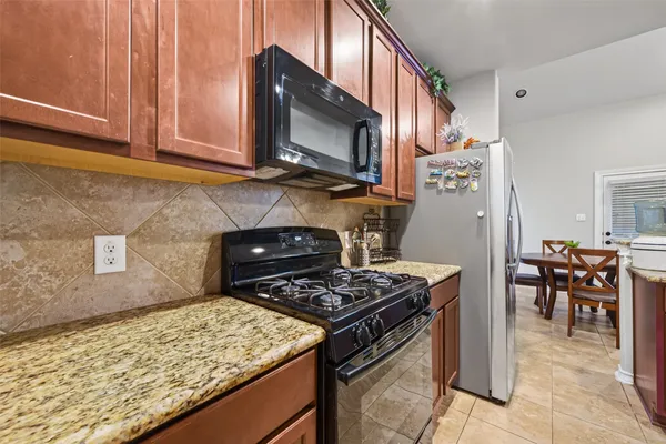 a kitchen with stainless steel appliances granite countertop a stove top oven a sink a dining table and chairs with wooden floor