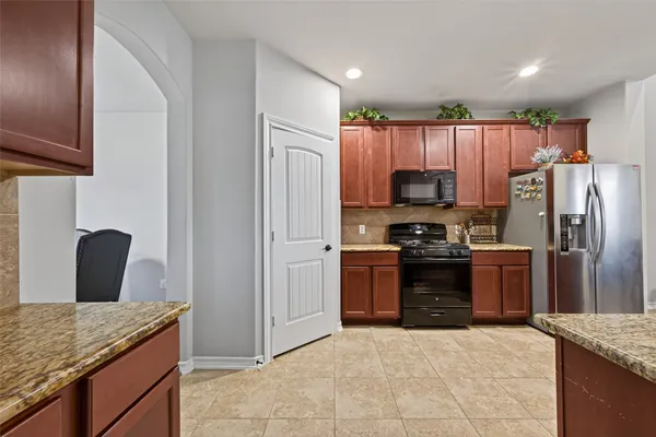 a kitchen with granite countertop a refrigerator stove and oven