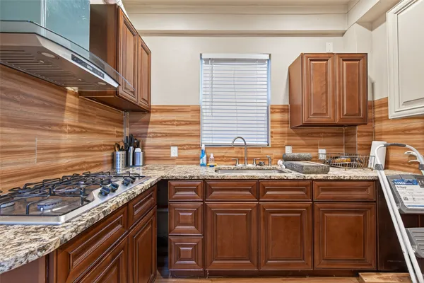 a kitchen with kitchen island granite countertop wooden cabinets and a stove top oven