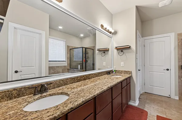 a bathroom with a granite countertop sink a mirror and a shower