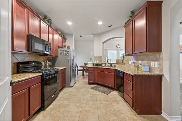 a kitchen with stainless steel appliances granite countertop wooden cabinets a stove top oven a sink and dishwasher