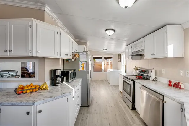 a kitchen with stainless steel appliances granite countertop a lot of counter space and wooden floors