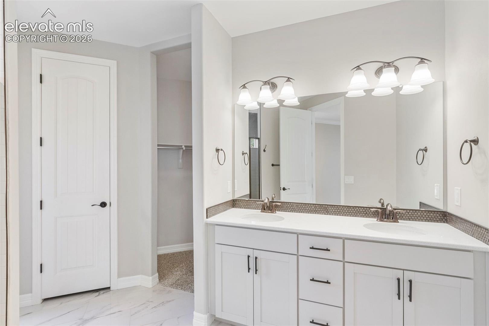 5375 Old Star Ranch View Colorado Springs, CO 80906 - Photo 26 of 47 Dual vanity featuring white cabinetry, integrated sinks, white countertops, and a mosaic tile backsplash