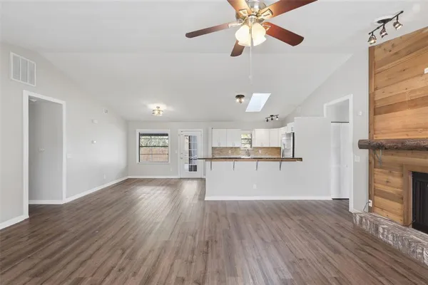 a view of a kitchen and an empty room with wooden floor