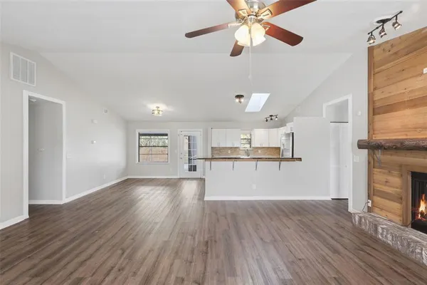 a view of a kitchen and an empty room with wooden floor