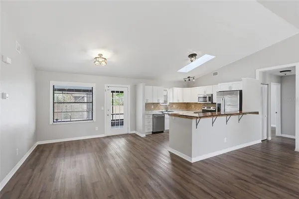 a kitchen with a refrigerator and white cabinets with wooden floor