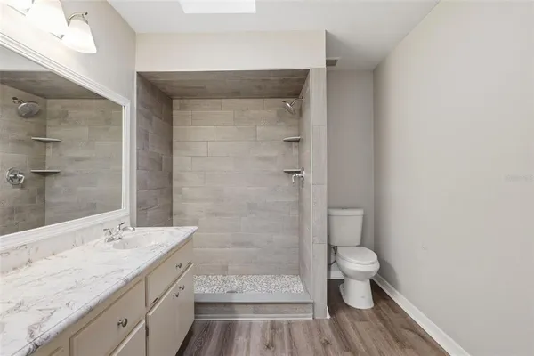 a bathroom with a granite countertop sink a toilet and shower