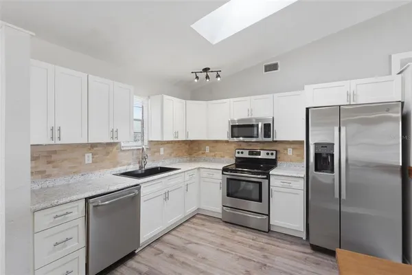 a kitchen with cabinets stainless steel appliances and wooden floor