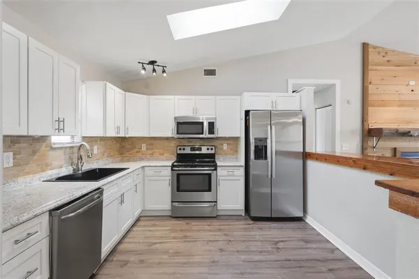 a kitchen with stainless steel appliances granite countertop a stove a sink and a refrigerator