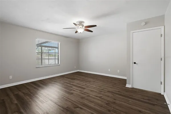an empty room with wooden floor chandelier fan and windows